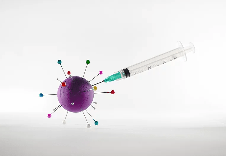 A needle injecting vaccine into an artistic depiction of SARS-CoV-2, the coronavirus that causes COVID-19. 